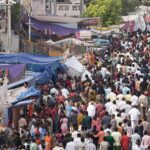 A dense crowd of visitors moving between stalls at a festival