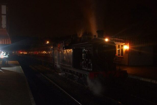 A steam train glowing with warm lights at a station at night