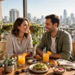 Couple enjoying a staycation breakfast on a sunny hotel balcony
